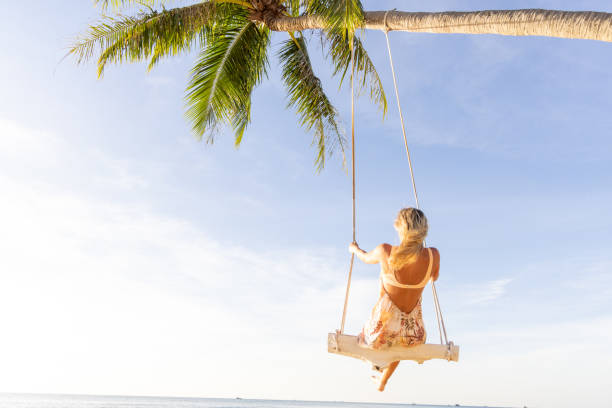 Woman Swinging Above a Tropical Beach at Sunset
