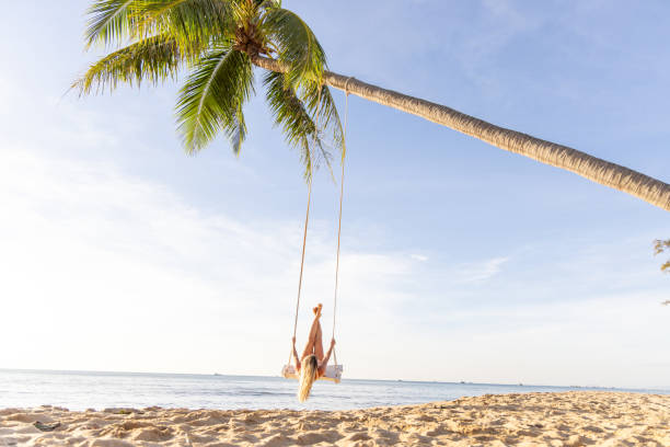 istock Woman Swinging Joyfully on a Palm Tree Swing at the Beach 2156072710