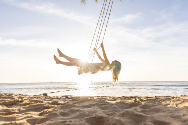 istock Woman Swinging Joyfully on a Beach at Sunset 2156072724