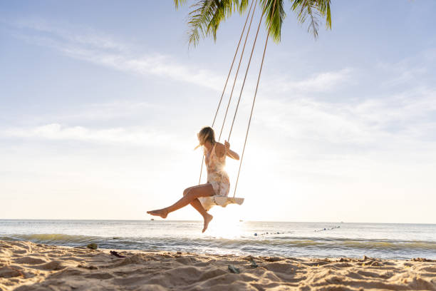 istock Woman Enjoying a Swing on a Tropical Beach at Sunset 2156072753