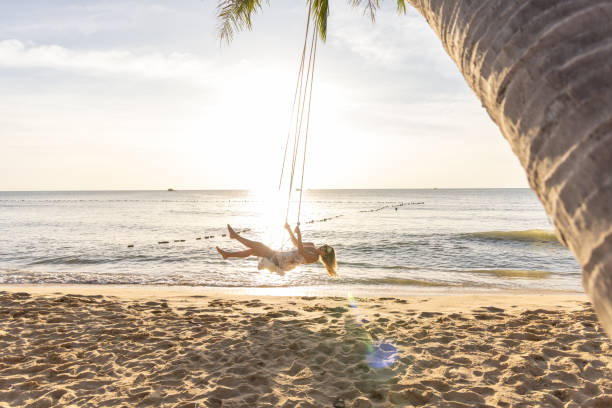 istock Woman Swinging Above the Beach at Sunset 2156072773
