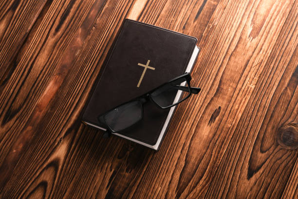 A reading glasses lying on the cover of the Bible, close up.