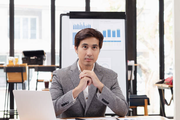 istock Asian businessman with laptop and analyzing a chart on a laptop while working in the office. 2156074351