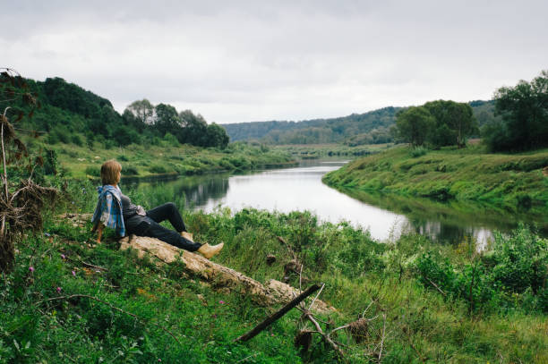 istock Woman resting on a stone on the river bank 2156077456