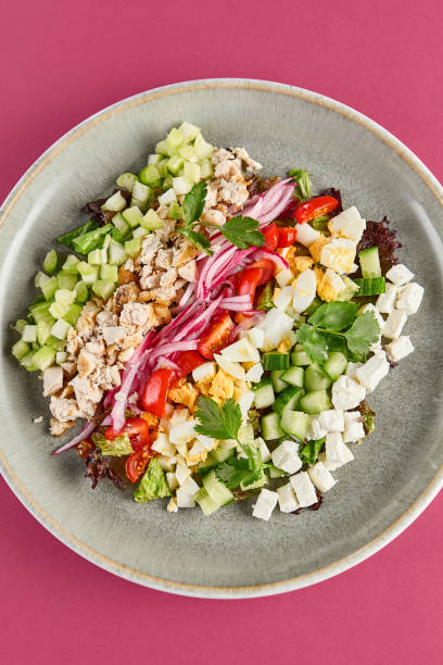 istock Fresh Cobb Salad with Chicken, Egg, and Vegetables on Pink Background 2156081460