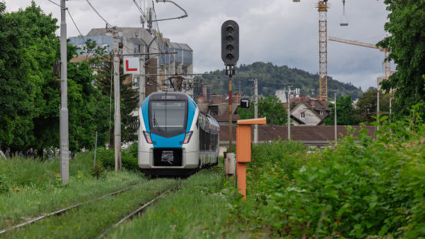 istock Modern passenger train is driving on poor and neglected train track. Green train track, leaves and grass growing out from the gravel trackbed. Unstable track 2156084326