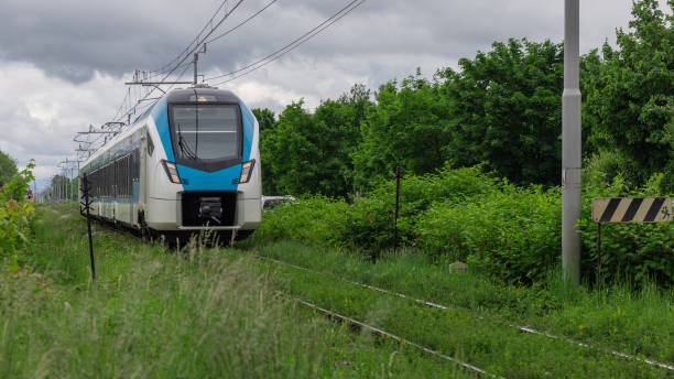 istock Modern passenger train is driving on poor and neglected train track. Green train track, leaves and grass growing out from the gravel trackbed. Unstable track 2156084341