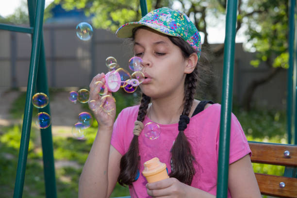 A girl blows soap bubbles on the street.