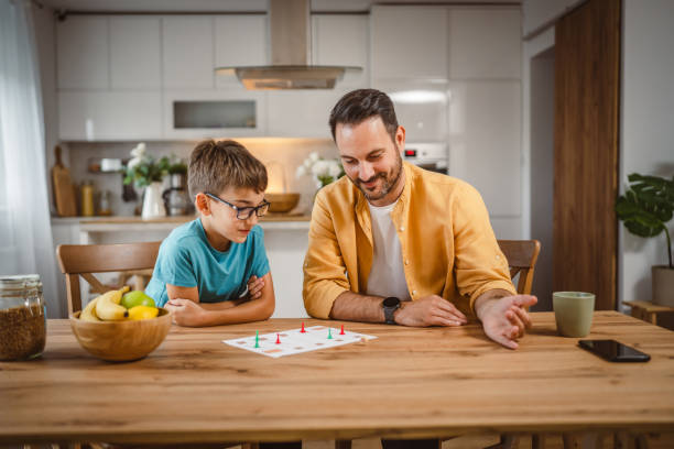 Father and son play board game have fun together at home