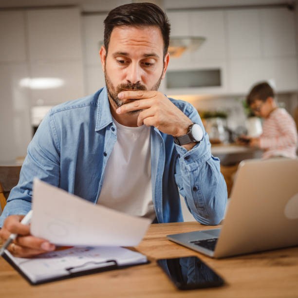 istock Exhausted man father work at home on laptop with son in the background 2156086743