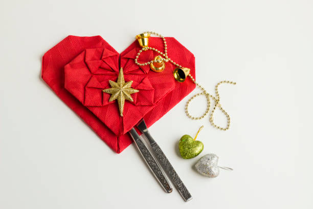 Close-up taken of Red color heart shape napkins on white with cutlery set,copy space and christmas ornaments