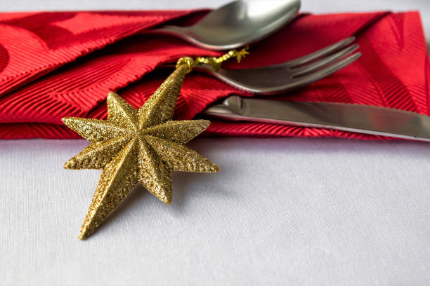 Close-up taken of selected silvery yellow star on the christmas table near luxury red paper napkin.White background