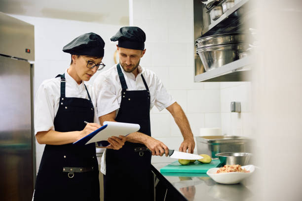 istock Two cooks going through a list while preparing food in kitchen at restaurant. 2156105430