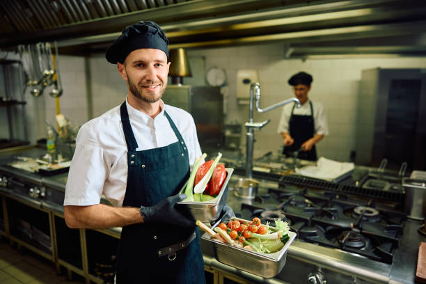 istock Smiling cook with fresh vegetables in the kitchen looking at camera. 2156105492
