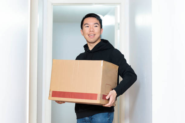 istock A man is standing in front of a door, holding a rectangular cardboard box 2156108812