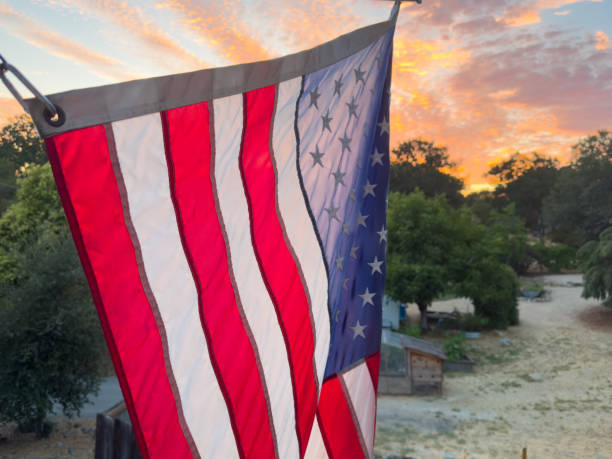 istock American Flag lit from behind with beautiful orange sunset in background 2156111963
