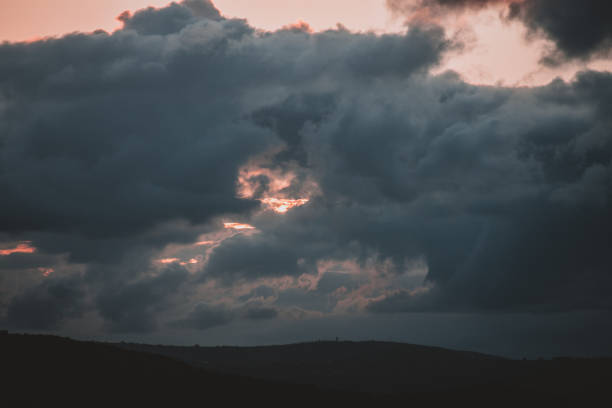 A dramatic and moody sunset with dark clouds rolling over the South African hills. Perfect for nature and travel content, this photo captures the serene yet powerful beauty of the landscape.