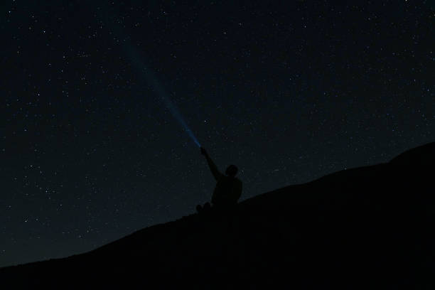 istock Man shines lantern in the sky. man with flashlight point to the starry sky at midnight. 2156112754