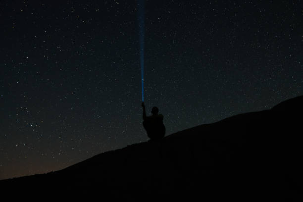 istock Man shines lantern in the sky. man with flashlight point to the starry sky at midnight. 2156112755