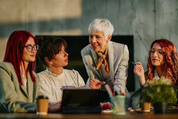 istock Old female manager teaching and coaching her young team at boardroom. 2156113966