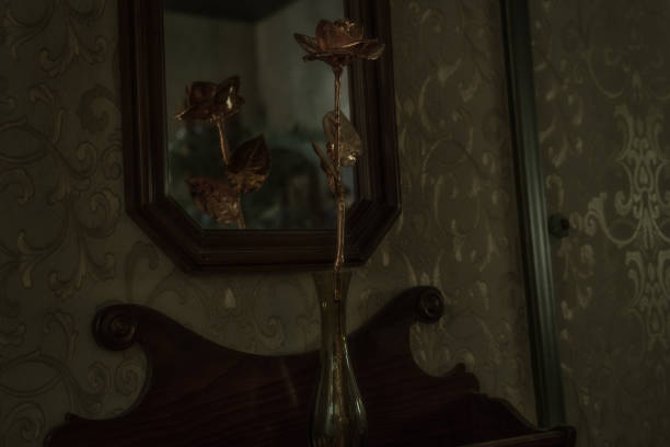 This image shows a real rose coated in gold, displayed on a curated wood shelf and reflecting in a mirror.