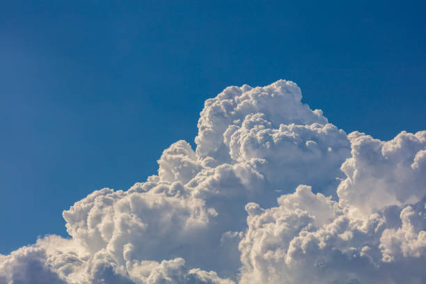 Closeup of Billowy cumulus clouds. Wispy clouds, deep blue sky in background.