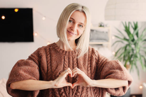 istock Smiling Middle-aged Woman makes a Heart Sign with her hands 2156119484