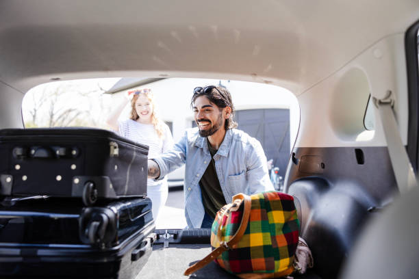 istock Young adult male smiles while loading their suitcases into the car 2156120701