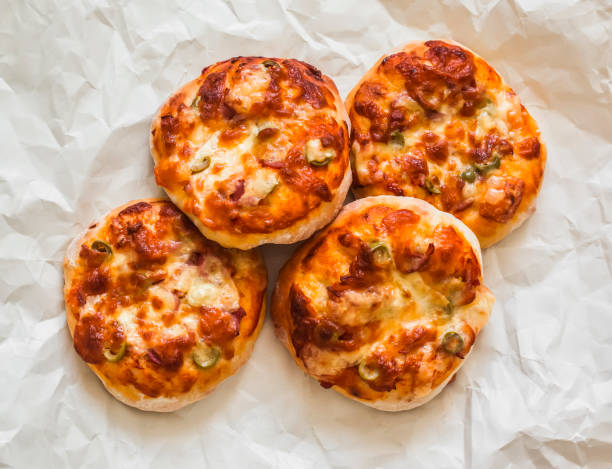 Mini pizza with ham, olives and mozzarella - a delicious snack, tapas on a light background, top view