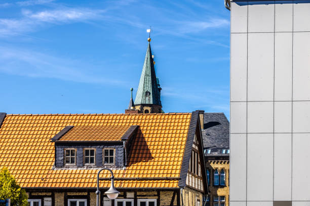 Traditional and modern house facades and churchtower - concept of architectures contrast in german city Goslar.