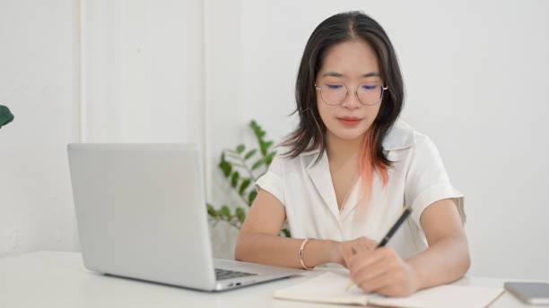 istock A focused young Asian female student doing homework or studying online in a coffee shop. 2156128347