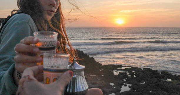 Friends enjoy tea at sunset on beach