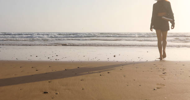 istock Young woman walks along beach at sunrise 2156128495