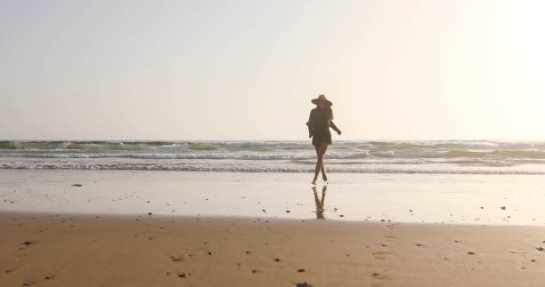 istock Young woman runs along beach at sunrise 2156128550