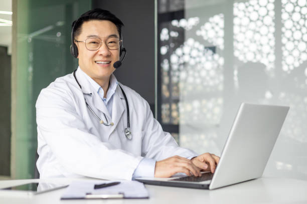 istock Smiling Asian doctor offering virtual consultation from his modern office 2156129404