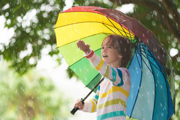 istock Child playing in rain. Kid jumping in puddle. 2156146338