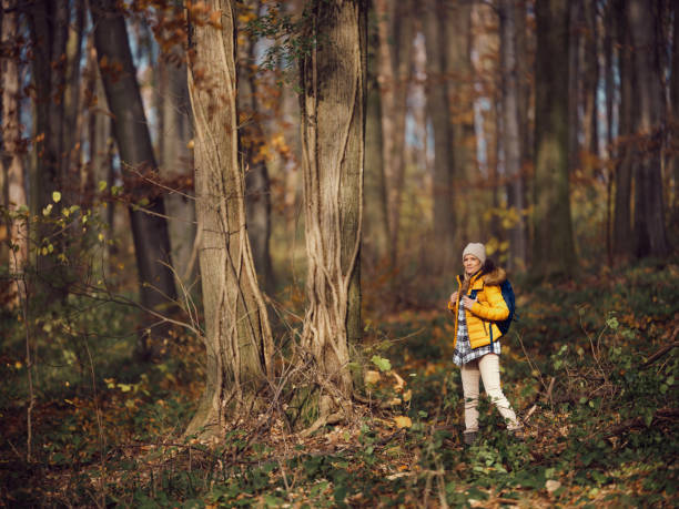 Smiling female backpacker enjoying while walking through the woods in autumn day. Photographed in medium format.