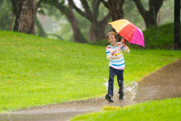 istock Child playing in rain. Kid jumping in puddle. 2156147245