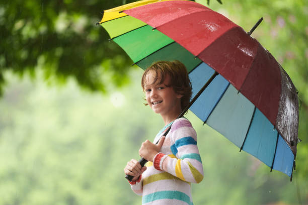 istock Child playing in rain. Kid jumping in puddle. 2156147411