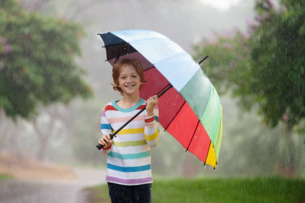istock Child playing in rain. Kid jumping in puddle. 2156147430
