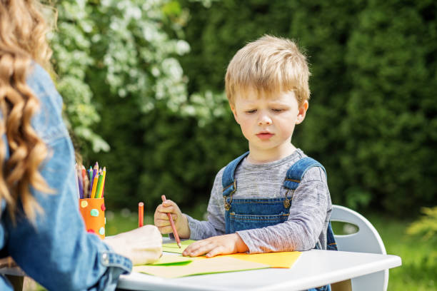 istock Focused child drawing with babysitter outside. Early years. Baby development. 2156147609