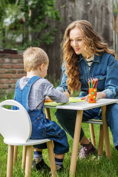 istock Mother and kid drawing at garden table. Early years. Baby development. 2156147626