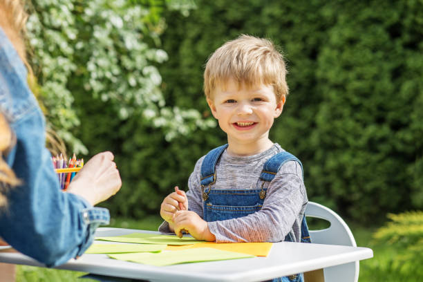 istock Smiling child coloring with mother outside. Early years. Baby development. 2156147634