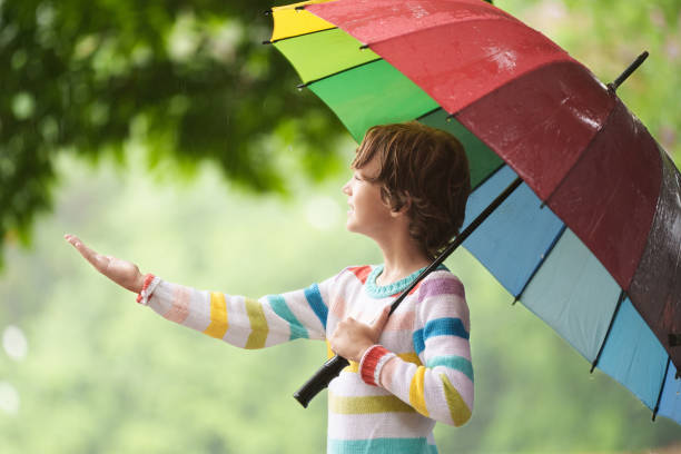 istock Child playing in rain. Kid jumping in puddle. 2156148975