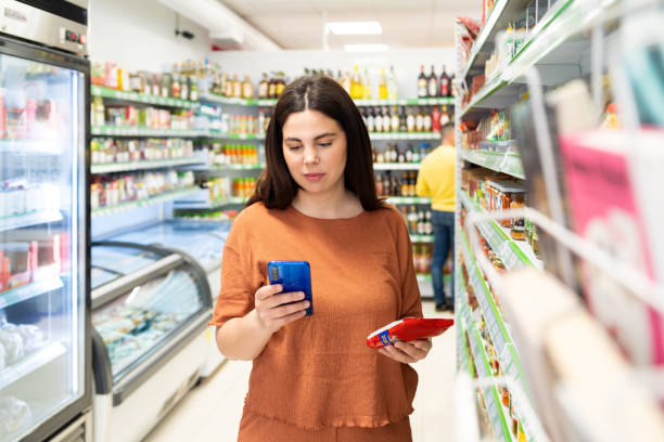 Woman using phone standing in the supermarket