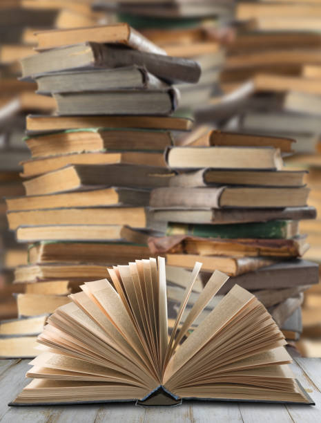 istock A Single Open Book Resting Against a Towering Stack of Volumes 2156153385