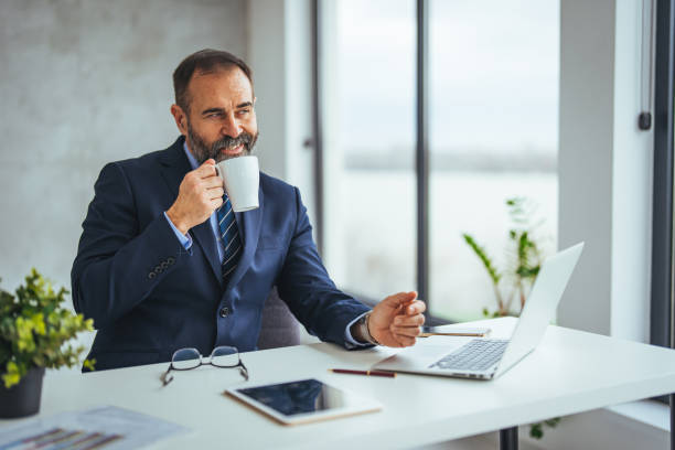 istock Senior Business Executive Enjoying Coffee Break at Desk 2156153958