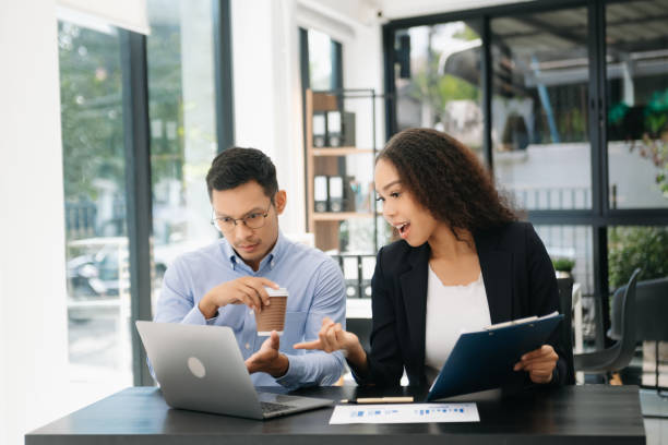 istock Asian business colleague business presents and explains and using laptop and tablet. Teamwork, financial marketing team, while sitting in office 2156156975