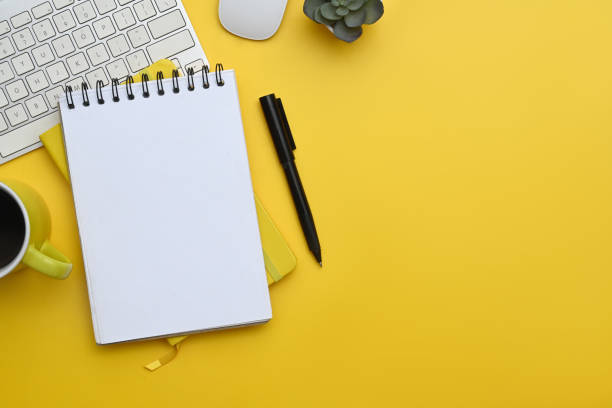 istock Laptop, notepad, coffee cup and financial reports on yellow background. Top view with copy space 2156159409