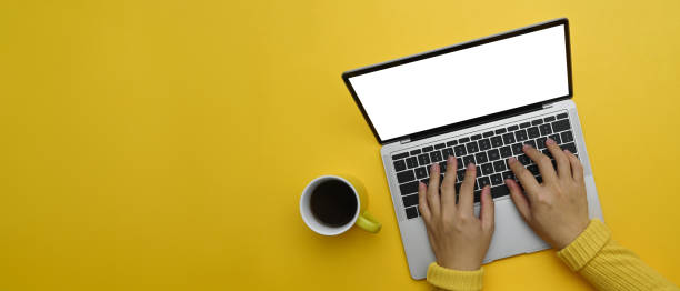 istock Woman hands typing on laptop keyboard over yellow background with copy space 2156159412
